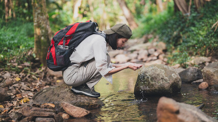 female tourist walking in nature meets a stream.happy women enjoying nature travel.female traveler carrying a backpack.Hiking tourists use  to travel.