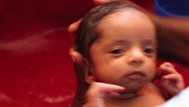 Indian little newborn baby is taking a bath on the arms of her mother. 4k video footage