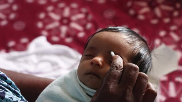Indian little newborn baby putting make up kajal eye brow after taking a bath on the arms of her mother.  4k video footage 