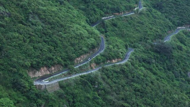 Long winding mountain road leading through rural countryside in Munnar Kerala India. Mountain highway with sharp hairpin turns on a fogy rainy day. Dangerous road to drive accident prone.