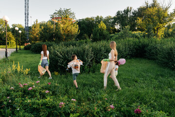 A group of adults and children together at sunset is engaged in garbage collection in the park....