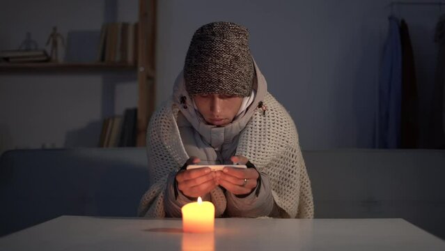 Shutdown of heating and electricity, young man feeling cold in his house, power outage, blackout, load shedding. energy crisis