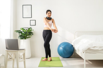 Fototapeta na wymiar Portrait sport asian beauty body slim woman in sportswear sitting relax and girl practicing yoga and do fitness exercise with laptop computer in bedroom at home.Diet concept.Fitness and healthy