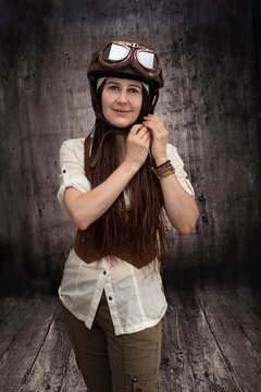 Portrait of a 50 year old woman in vintage biker or aviator outfit with helmet and glasses