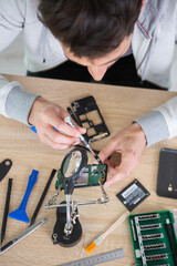 man repairing broken smartphone in workshop