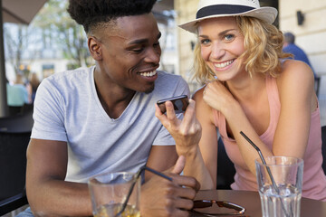 couple on a coffee terrace drinking watching on the phone
