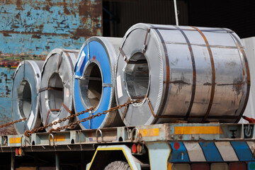 Roll of rolled steel sheet on transport truck. metal coils with fastener on truck ready for delivery to steel factory yard. - obrazy, fototapety, plakaty