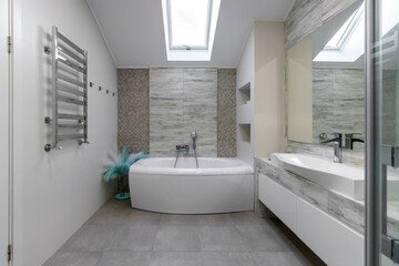 Bathroom with a shower cabin, a large mirror and a chrome heater or a radiator of a towel against a white wall. Loft style in a new apartment