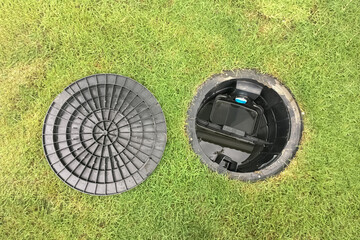Image of a septic tank grease trap for home use to help collect light liquids such as fats, oils, and grease from the kitchen buried underground with green grass cover. - 544007890