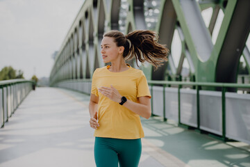 Young woman jogging at city bridge, healthy lifestyle and sport concept.