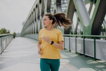 Outdoor-Kissen Young woman jogging at city bridge, healthy lifestyle and sport concept. © Halfpoint
