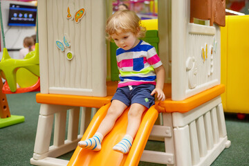 Little boy riding on slide at indoor play center