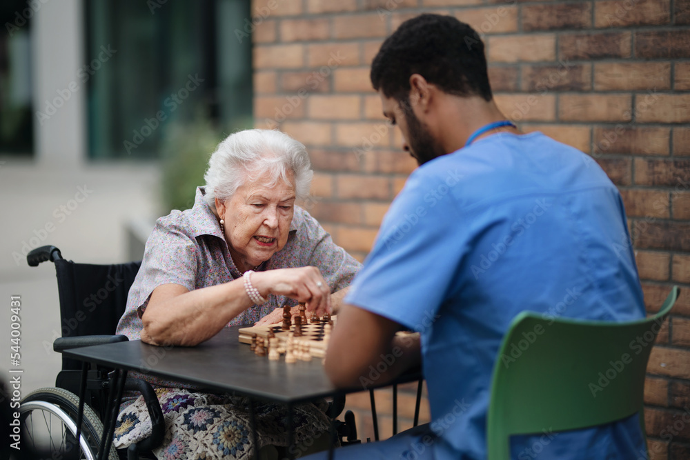 Wall mural Caregiver playing chess with his client outdoor at cafe.