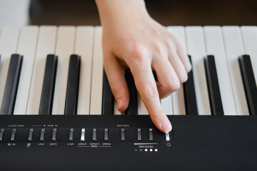 An adult woman plays an electric piano, hands close-up. Female hands on the buttons of a portable...