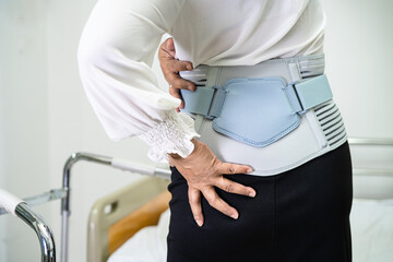Asian lady patient wearing back pain support belt for orthopedic lumbar with walker.
