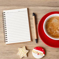 Blank notebook, black coffee cup, Christmas cookies and pen on wood table, Top view and copy space. Xmas, Happy New Year, Goals, Resolution, To do list, Strategy and Plan concept
