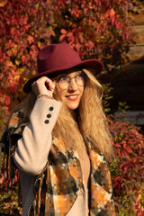 An elegant young woman in autumn clothes and a red hat and glasses. Large portrait