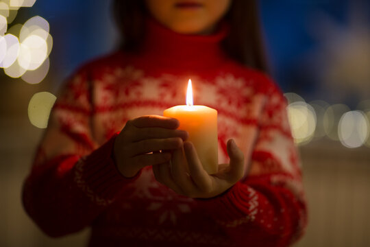 burning candle in hands of child for christmas at home