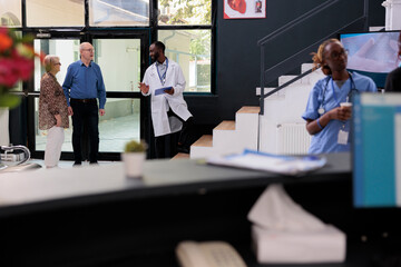 African american physician explaining health care treatment to elderly couple before leaving hopsital looby. Patients having checkup visit appointment, medicine service and concept