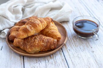 A cup of coffee and croissant on white table