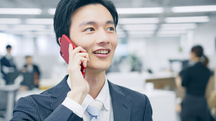 オフィスでスマホ通話するビジネスマン