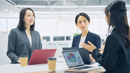 スタンディングミーティングする女性会社員グループ