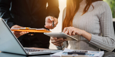 Businessman hand using smartphone, laptop and tablet with social network diagram and two colleagues discussing data on desk as concept