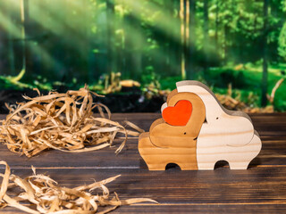 Wooden puzzle in the form of a family of handmade elephants on the background of the forest.