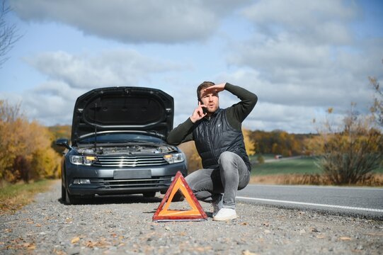 Handsome young man with his car broken down by the roadside