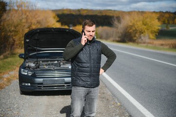 A man calls a phone number to talk to a mechanic. The car broke down on the roadside. The concept for fix, help, problem, repair. blurred background.