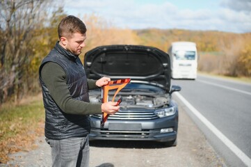 A young man with a black car that broke down on the road,copy space.