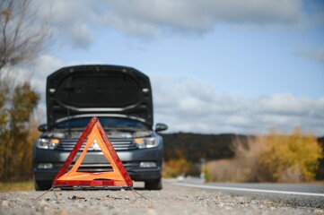 breakdown triangle stands near a broken car.