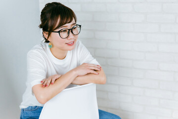 部屋で椅子に座るメガネをかけた日本人女性
