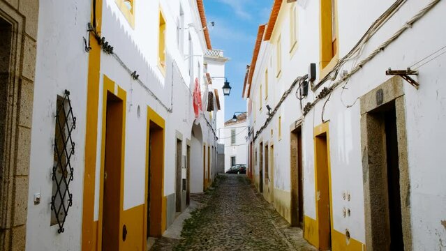 Discovering the narrow and picturesque streets of Evora, Portugal, featuring the famous whitewashed houses with yellow accents