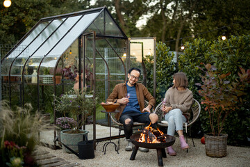 Young couple have a dinner by the fire at backyard - Powered by Adobe