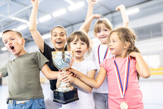 Cheerful students celebrating victory with teacher at school sports court