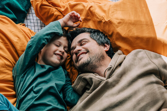 Smiling boy with father lying on bed at home