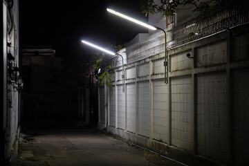 A dark alleyway with lantern and a fence
