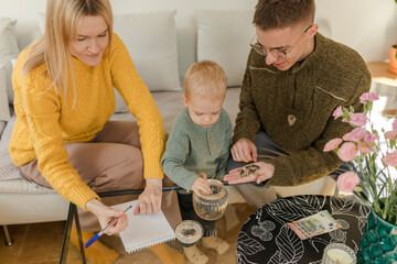 Parents with son counting coins in living room at home