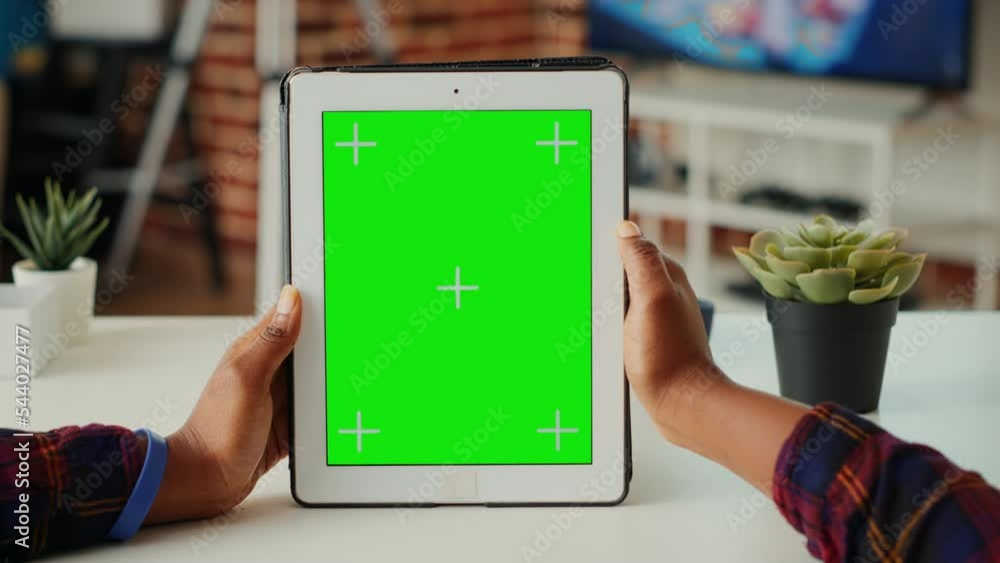 Poster office employee vertically holding wireless device with greenscreen display, looking at chroma key t