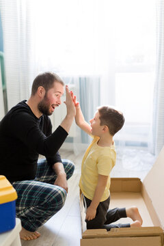 Father giving high-five to son in box at home
