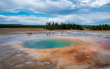 Scenic view of beautiful Grand Prismatic Spring with cloudy sky in background. Geothermal landscape in Midway Geyser Basin during summer. Famous tourist attraction at Yellowstone national park.