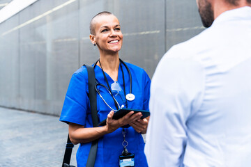 Smiling nurse with tablet PC talking to doctor