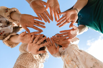 Young friends showing palms under blue sky