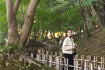 Fototapeta premium 日本庭園を散策しながら写真を撮る女性