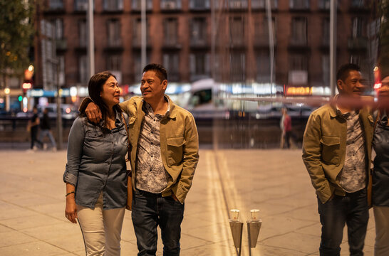 Smiling Mature Couple Walking On Footpath At Night