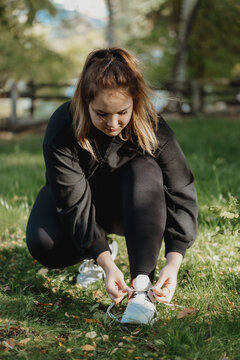 Young Woman Tying Shoe Lace In Park