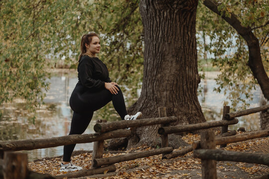 Plus sized woman exercising in autumn park