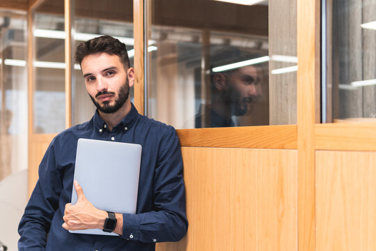 Businessman with laptop leaning on wall