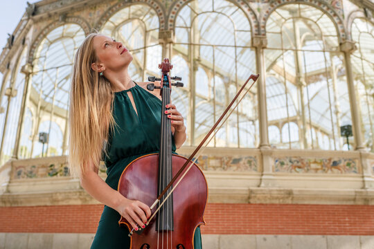 Young woman playing cello in front of building
